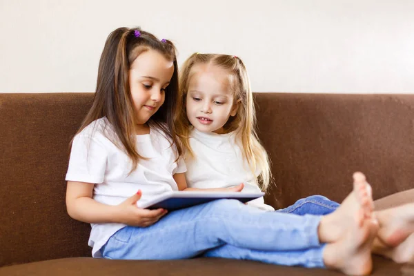 Twee Schattige Zusjes Spelen Met Digitale Tablet Zittend Bank Thuis — Stockfoto
