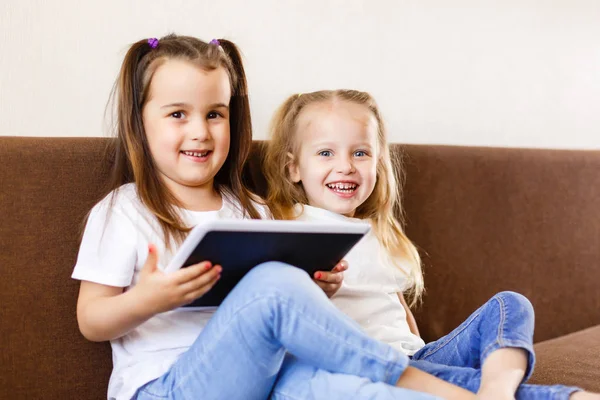Dwa Urocze Małe Siostry Grając Cyfrowym Tablet Siedząc Kanapie Domu — Zdjęcie stockowe