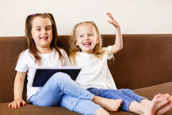 Dwie Dziewczynki Pomocą Płytki Dotykowej Smartphone Siedzi Kanapie Domu — Zdjęcie stockowe