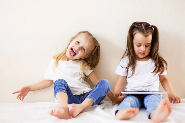 Dwie Małe Dziewczynki Zabawy Siedzi Łóżku Pomocą Cyfrowego Tabletu — Zdjęcie stockowe