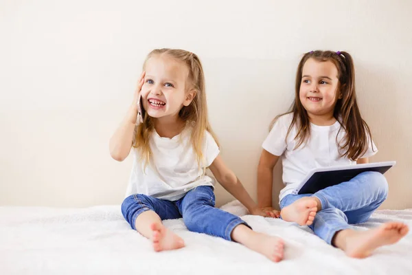 Dwie Dziewczynki Pomocą Płytki Dotykowej Smartphone Siedzi Kanapie Domu — Zdjęcie stockowe