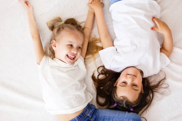 白いベッドの上に横たわる つの幸せ少し姉妹トップ ビュー — ストック写真
