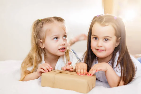 Twee Kleine Lachende Zusters Liggend Wit Bed Met Geschenkdoos — Stockfoto