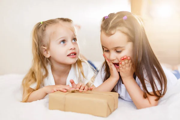 Twee Kleine Lachende Zusters Liggend Wit Bed Met Geschenkdoos — Stockfoto