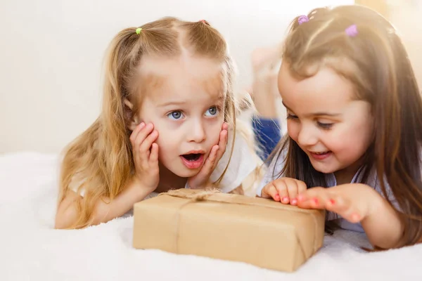 Twee Kleine Lachende Zusters Liggend Wit Bed Met Geschenkdoos — Stockfoto