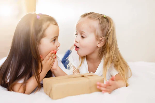 Twee Kleine Lachende Zusters Liggend Wit Bed Met Geschenkdoos — Stockfoto