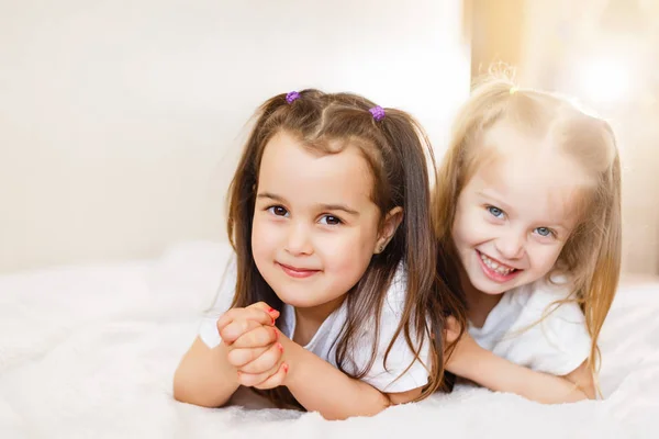 Dos Pequeñas Hermanas Sonrientes Encantadoras Tumbadas Cama Blanca — Foto de Stock