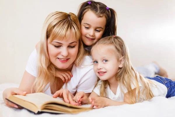 幸福的家庭观念 漂亮的年轻母亲读书给她的小女儿躺在床上 — 图库照片