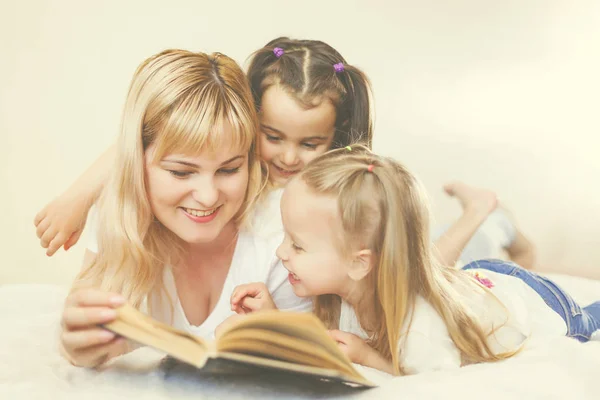 幸福的家庭观念 漂亮的年轻母亲读书给她的小女儿躺在床上 — 图库照片
