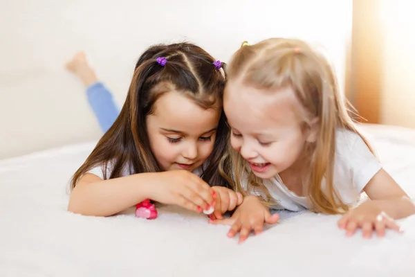 二人の少女が自宅のベッドの上に横たわる自分の爪を塗る — ストック写真