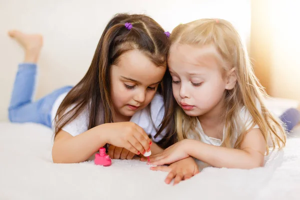 二人の少女が自宅のベッドの上に横たわる自分の爪を塗る — ストック写真