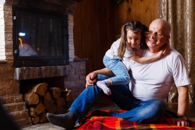 mutlu küçük kız sıcak şömine oturan onun dedesi sarılma