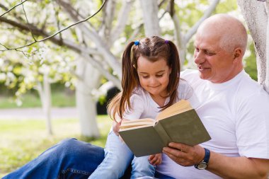 Çiçek bahçesinde oturan okuma onun torunu ile mutlu Büyükbaba