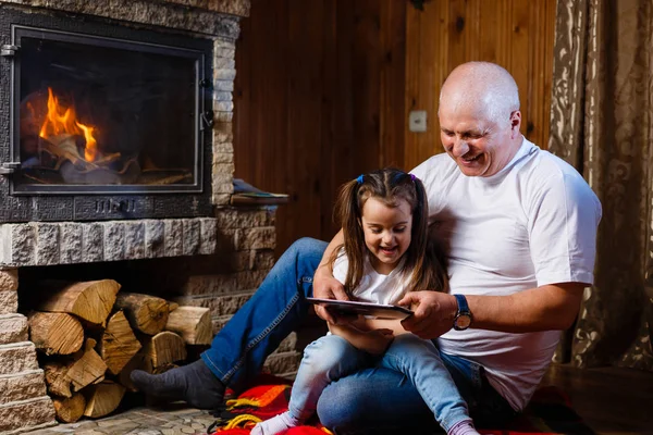 Děda Vnučka Zábava Pomocí Digitálních Tabletu Posezení Krbu — Stock fotografie