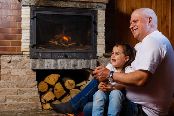 Grandfather Granddaughter Having Fun Using Digital Tablet Sitting Fireplace — Stock Photo, Image