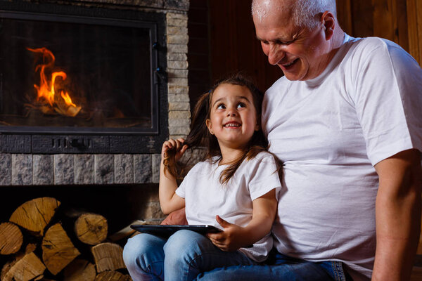 Grandfather and granddaughter spending time near fireplace