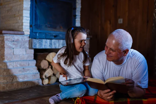 Grandfather Granddaughter Reading Book Using Tablet Lying Fireplace — Stock Photo, Image