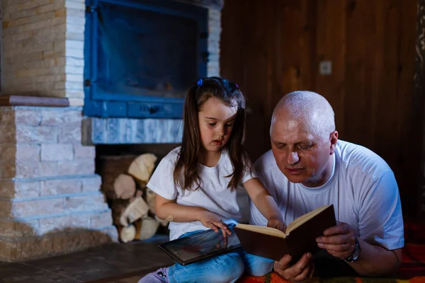 Grandfather Granddaughter Reading Book Using Tablet Lying Fireplace — Stock Photo, Image
