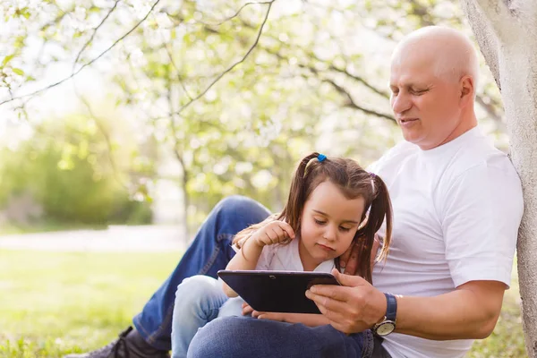 Nonno Abbracciare Nipote Utilizzando Tablet Digitale Seduto Nel Parco — Foto Stock