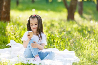 paket üzerinde oturan ve üzerinde yeşil çayır dondurma yeme küçük kız