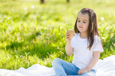 paket üzerinde oturan ve üzerinde yeşil çayır dondurma yeme küçük kız