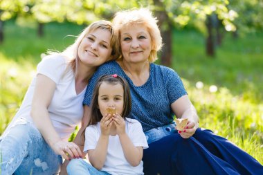 Yeşil park onun büyükannesi ve anne ile birlikte oturan dondurma yiyen çocuk 