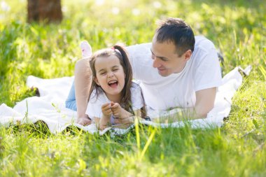 Genç baba ve kız eğleniyor yeşil çim üzerinde yalan