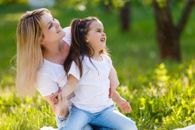 Anne ve kızı eğleniyor yeşil çayır üzerinde oturan dandelions ile oynarken