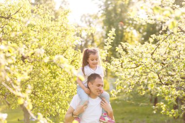 Genç adam onu yeşil park sırtında taşıyan kızının oynarken