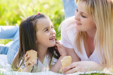 Mutlu anne ve kızı yeşil parkta vakit ve dondurma yeme