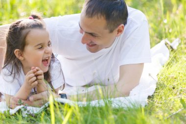 mutlu genç baba ve kızı yeşil çim üzerinde yalan