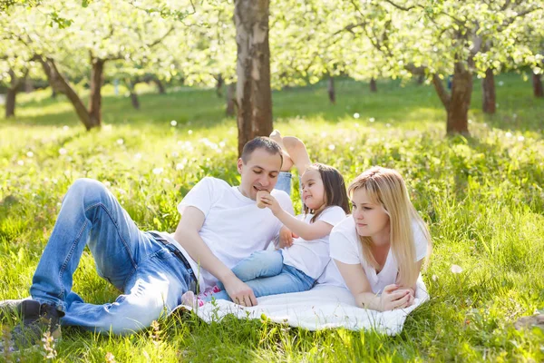公園の緑の草原に横たわっているアイスクリームを食べて幸せな家族 — ストック写真