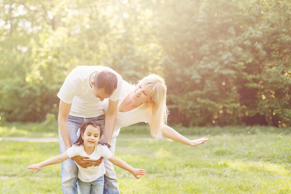 cute baby girl having fun with parents walking in park