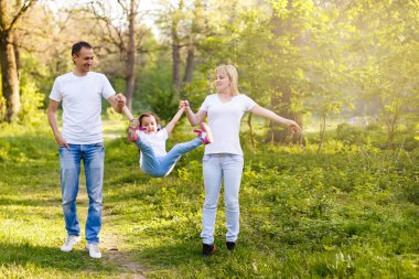 mutlu küçük kız anne güneşli park, tam uzunlukta yürüyüş ile tutuşup atlama