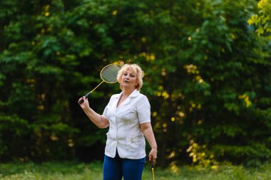yeşil park badminton raket ayakta tutan üst düzey kadın