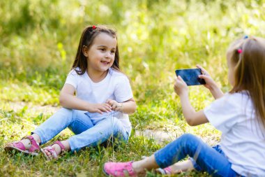 Küçük kız kardeşi ile smartphone açık havada fotoğraflarını yapar.