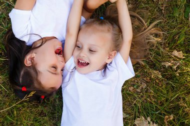 iki küçük gülümseyen kız parkta çim üzerinde yalan