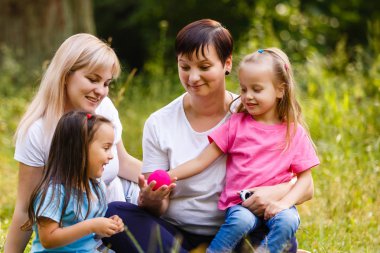 İki anne ve iki küçük kızı eğleniyor yeşil Park'ta dinlenme 