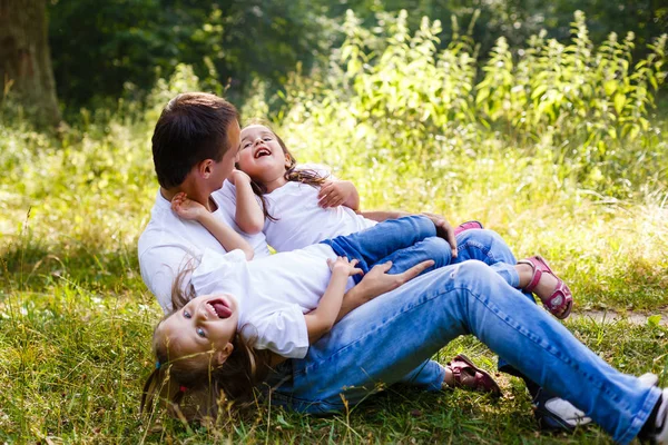 幸せなパパと 人の小さな娘は楽しんで緑豊かな庭園の上に座って — ストック写真