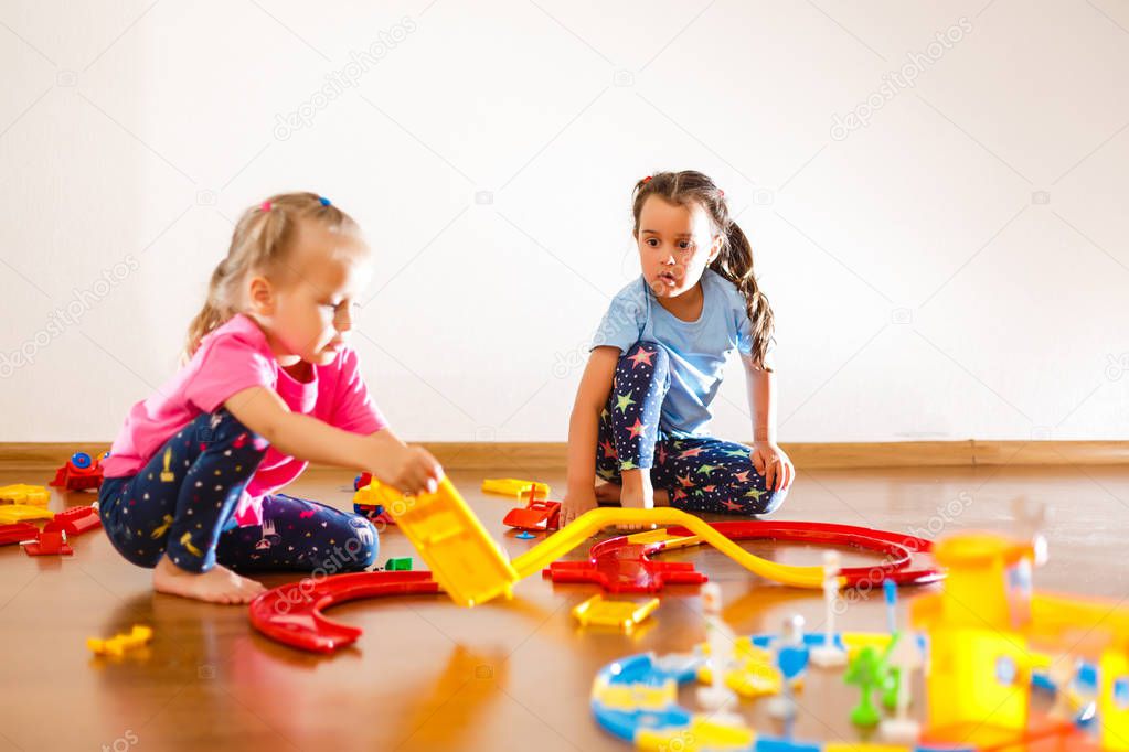 Two little girls playing in kindergarten sitting on floor