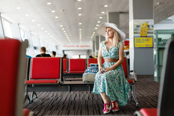 戴着帽子的年轻女子正在看着飞机上的窗户 等待机场的起飞 — 图库照片