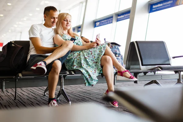 Pareja Joven Sentada Con Teléfono Reservar Sala Espera Aeropuerto — Foto de Stock