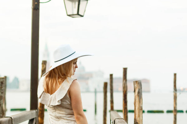 Young woman in white elegant dress posing in Venice at sunrise