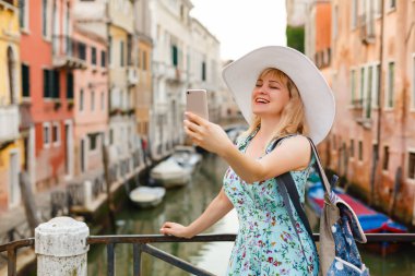 Genç kadın Gezgin selfie fotoğraf San Marco kare ile gondol Venedik, İtalya için arka plan üzerinde duran onun smartphone kullanarak yapma