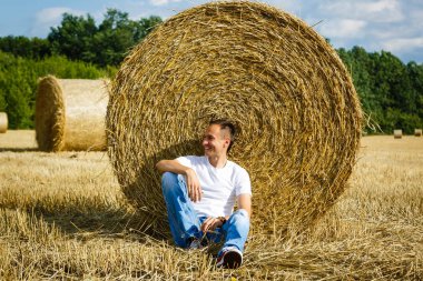 Açık saman balya oturan genç adam portresi