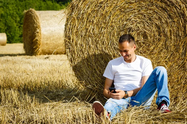 Feliz Hombre Sonriente Usando Teléfono Inteligente Sentado Cerca Pila Heno — Foto de Stock
