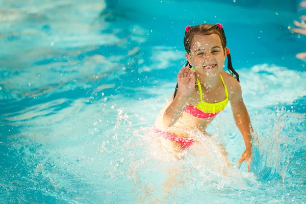 little girl in the water park swimming underwater and smiling