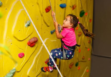 kapalı bir kaya duvarı tırmanma pembe tişört, küçük kız