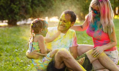 Baba, anne ve küçük kızı yeşil parkta oynarken ve boyalar ile duş
