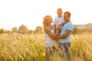 Yürüyüş ve yeşil alana günbatımında eğleniyor oğlu ile genç Aile